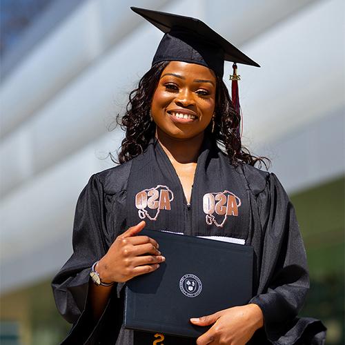 student graduating holding up diploma