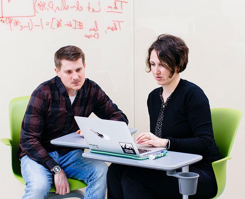 A faculty member talking to a student in an open study space