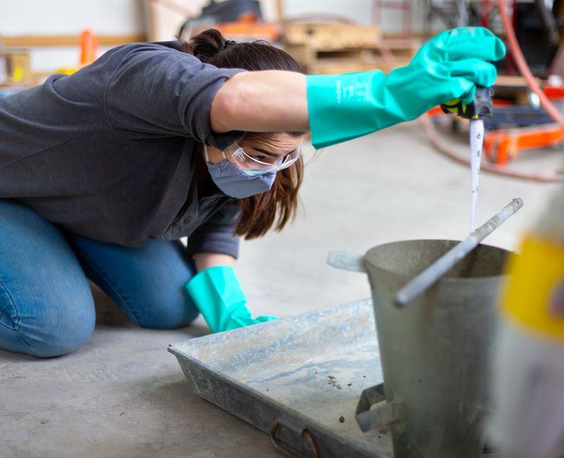 Student measuring concrete bucket in laboratory